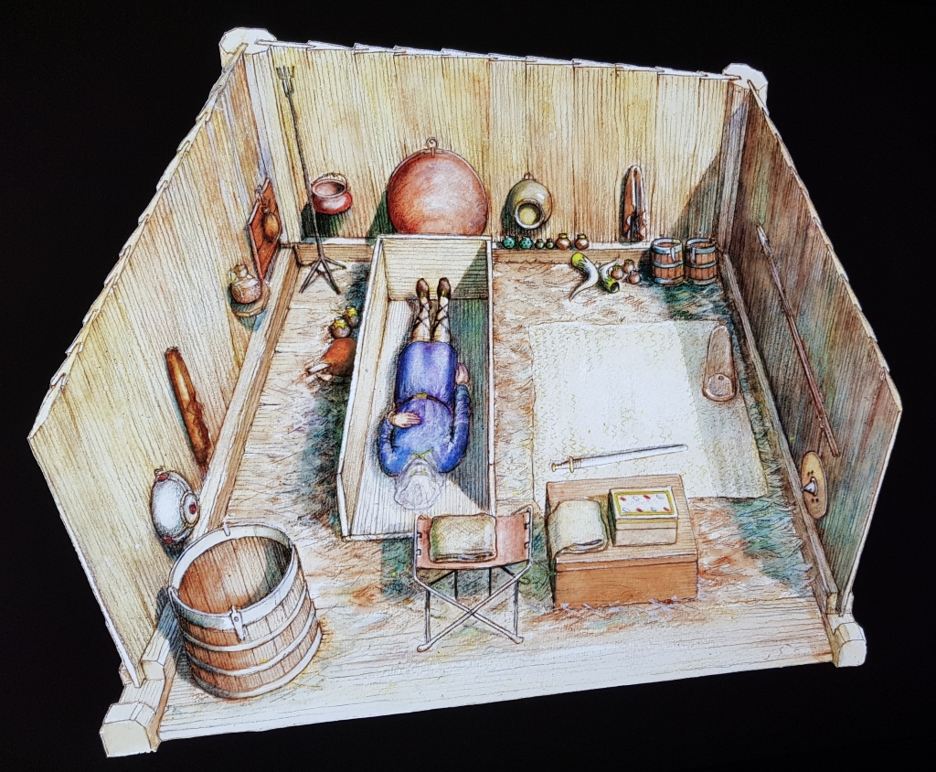 Reconstruction of the Prittlewell Prince's burial chamber showing a wood-lined chamber with a body in a wood coffin in the centre and various artefacts laid out around the walls.