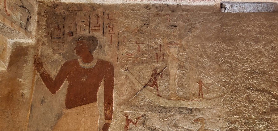 Hetepheres II (her mother) and Meresankh III undertake a Hathoric ritual of 'pulling the papyrus', in a papyrus boat above two lower registers of fattening geese and fishing and fowling on papyrus boats. To the left (north), the large figure of Prince Kawab, Meresankh III's father, occupies all three registers, wearing a short black wig with a bracelet and collar, above a long kilt. He faces north, with a long staff, showing his importance in his right hand.